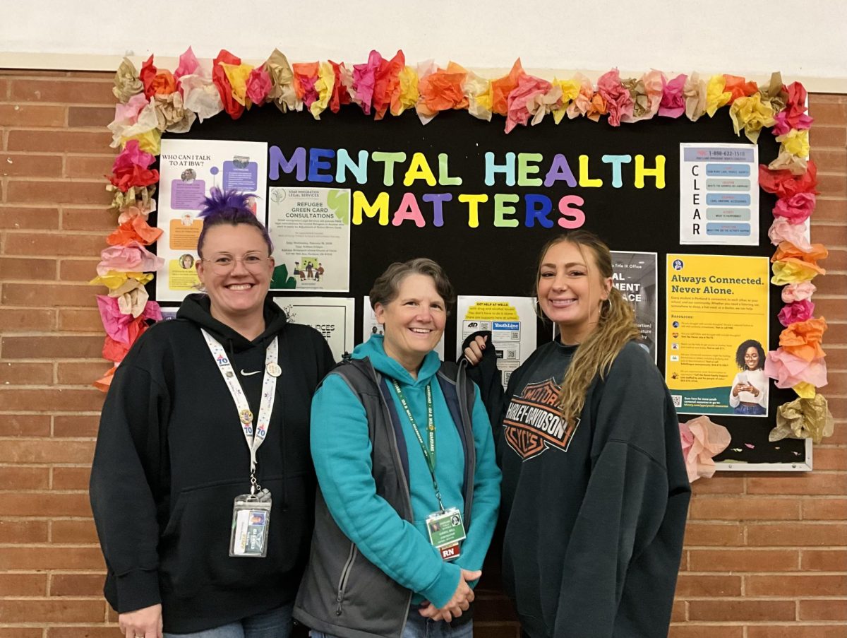 IBW's mental health support team, Emilee Refvem, Cheryl Bell and Britni Locke, pose in front of the mental health resources billboard.